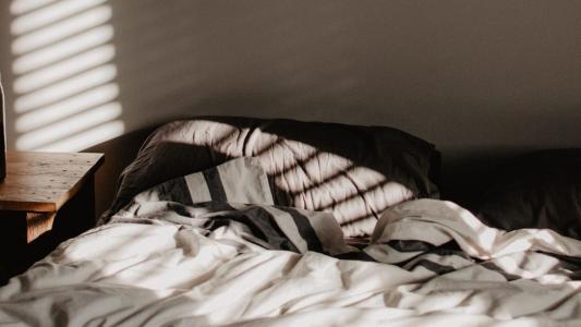 A bedroom with a bed and a lamp, where the history of insomnia has left its mark.