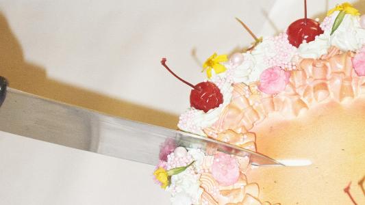 A person satisfying food cravings by cutting a cake with a knife.