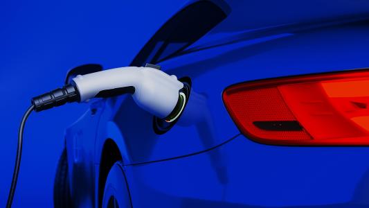 A blue electric car is plugged into an electric charger.