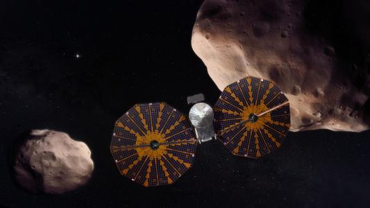 An artist's depiction of NASA's Lucy spacecraft with asteroids in the background.