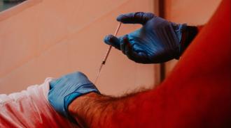 A man is getting a vaccine in a tent.