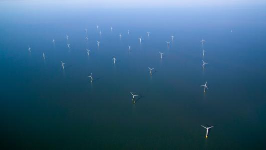 An aerial view of wind turbines in the ocean.