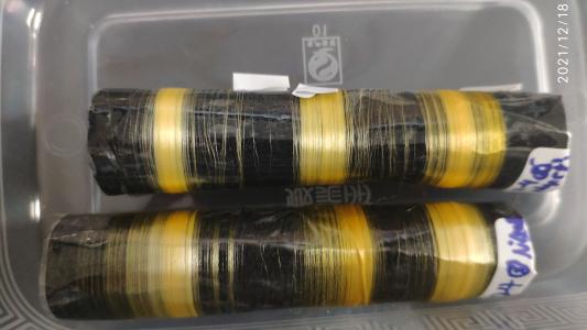 golden silk fibers produced by transgenic silkworms wrapped around black cylinders