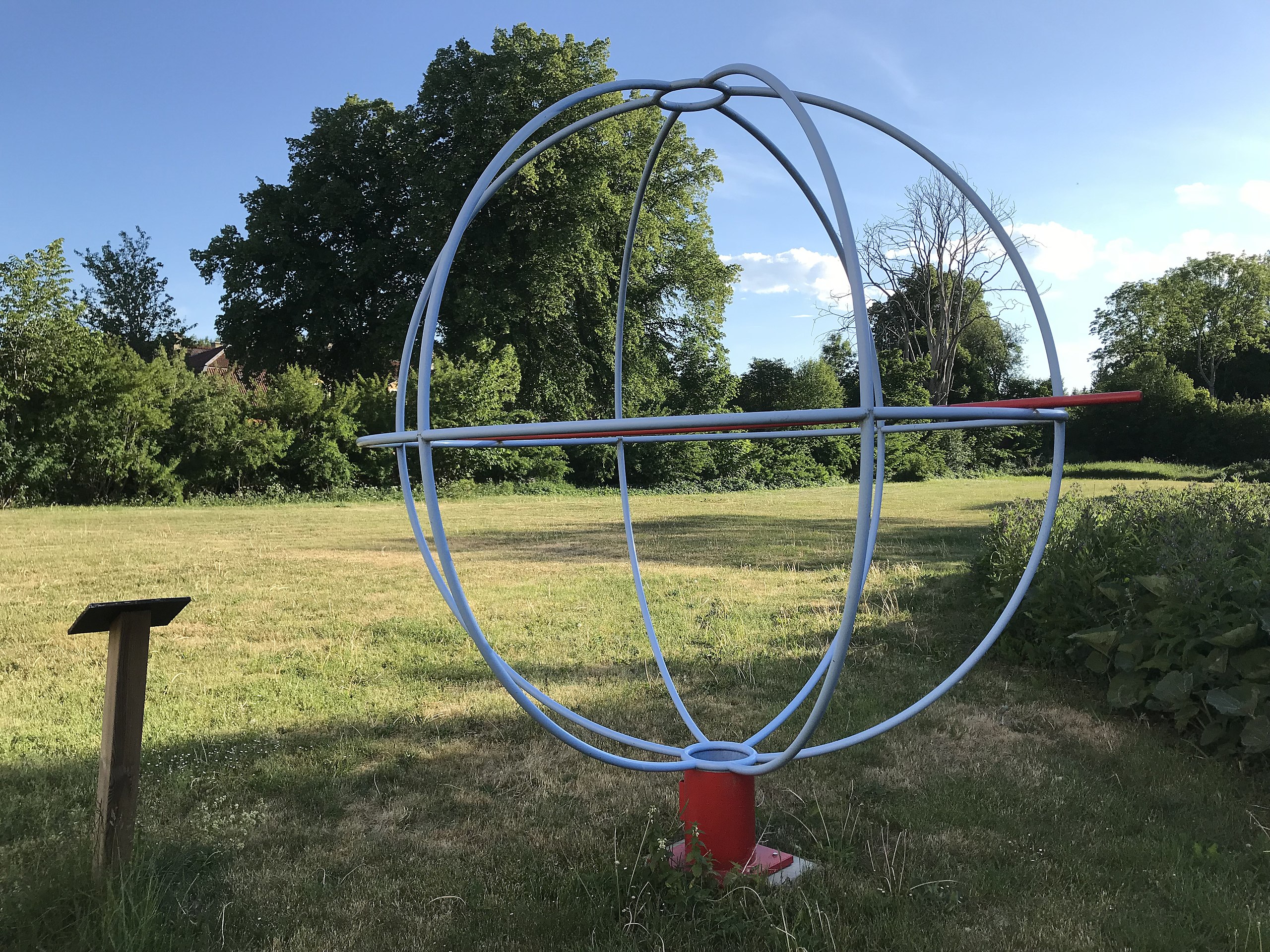 a red and blue sculpture in a grassy field.