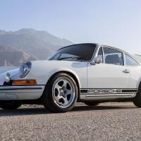 A white porsche 911 parked in front of wind turbines.